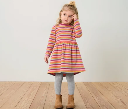 Ein Mädchen trägt ein Kinder-Sweatkleid mit Streifenmuster.
