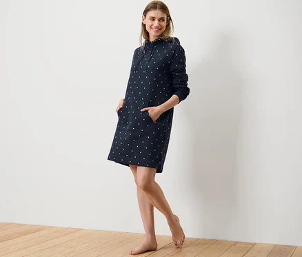 Frau posiert in einem Loungewear-Kleid mit Punkten.
