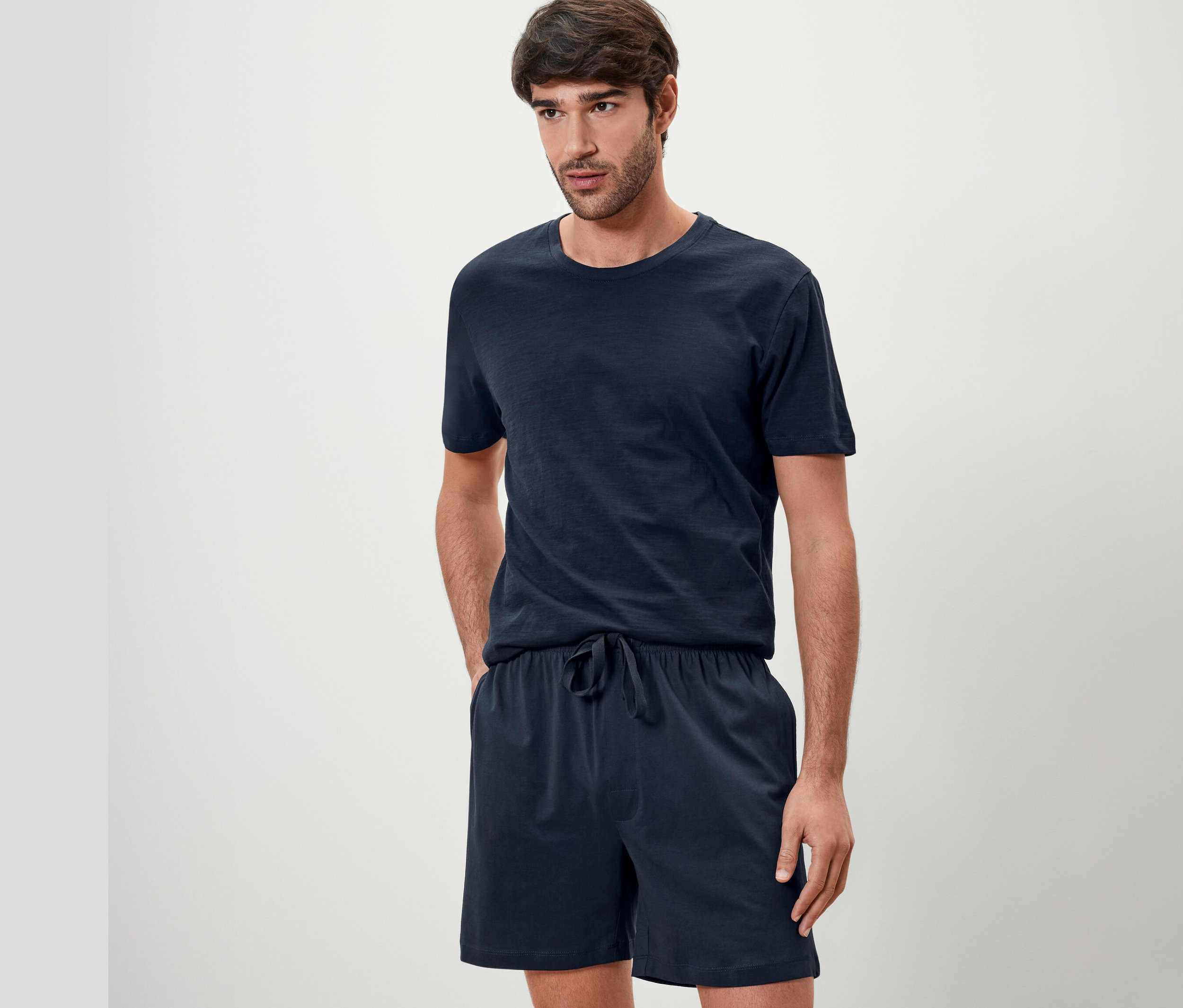 Mann posiert im dunkelblauem Shorty-Pyjama-Set.