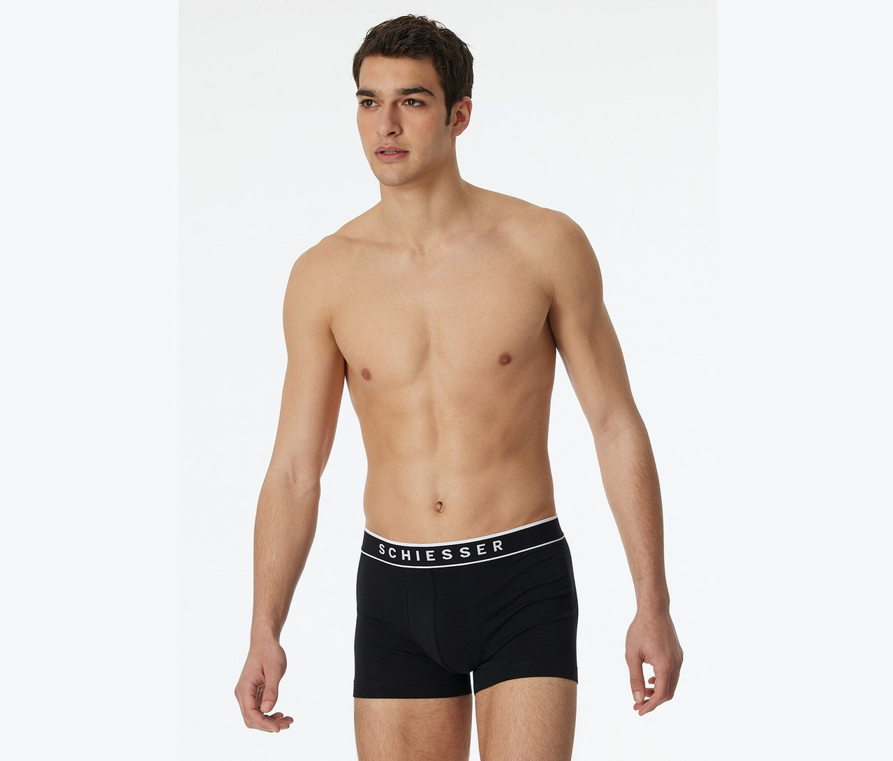 Mann posiert ohne Hemd in schwarzen Schiesser Boxershorts.