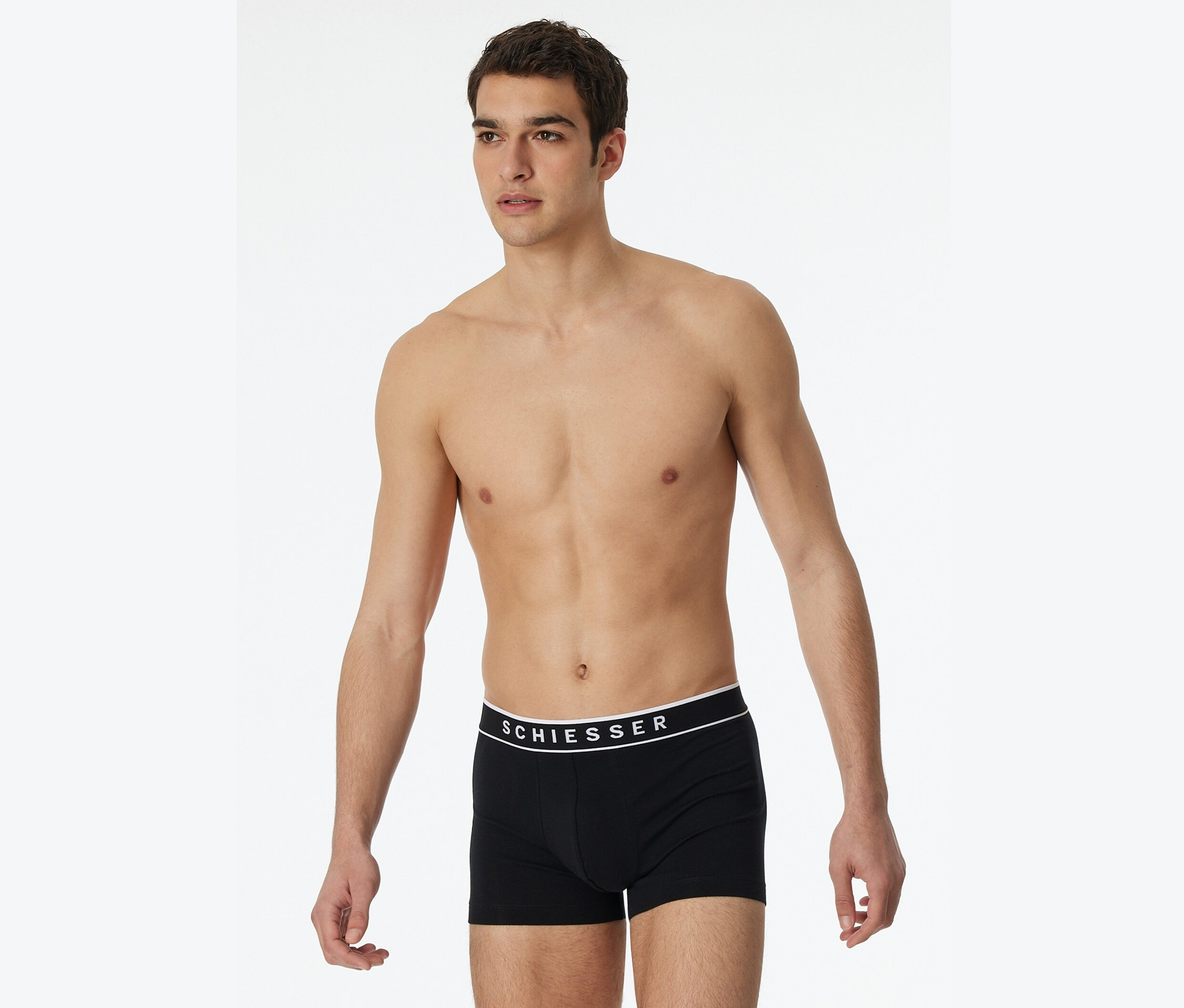 Mann posiert ohne Hemd in schwarzen Schiesser Boxershorts.