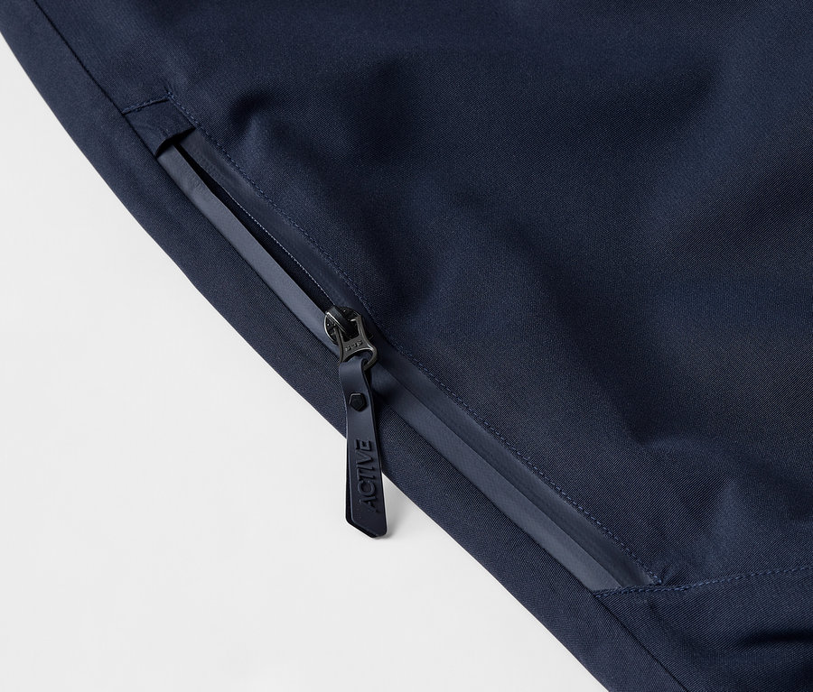 Detailaufnahme einer dunkelblauen Jacke mit Reissverschluss und Logo.