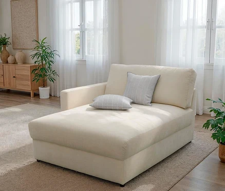 Cremeweißes Sofa mit Armlehne auf einer Seite und zwei grauen Kissen.