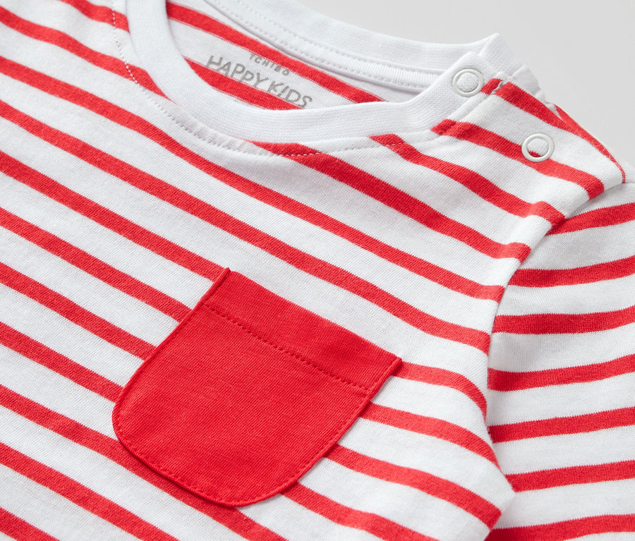 Detailansicht eines Kinder-Langarmshirts mit roten und weißen Streifen und einer roten Tasche.