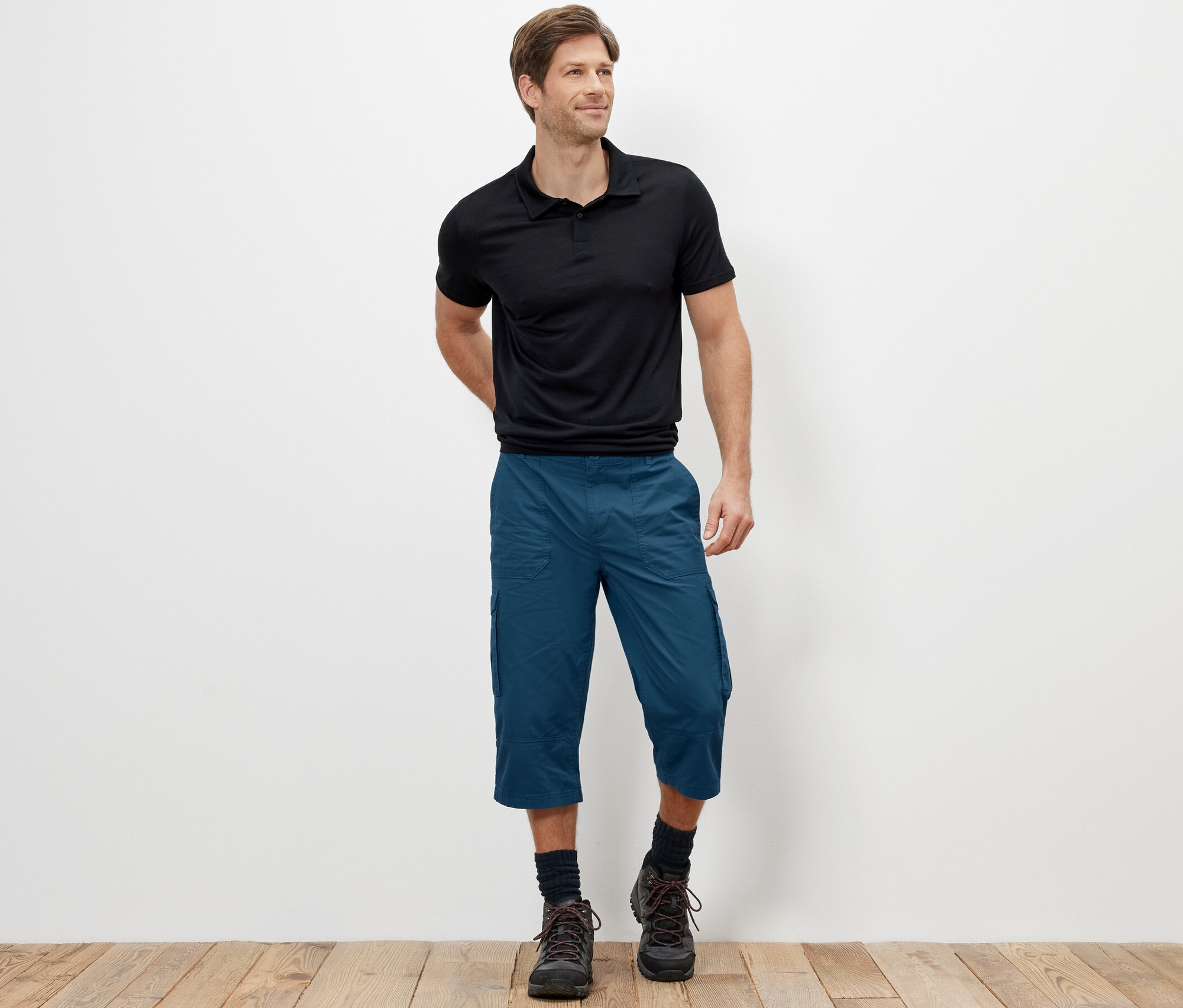 Mann steht und trägt blaue 3/4-Cargo-Bermudas.