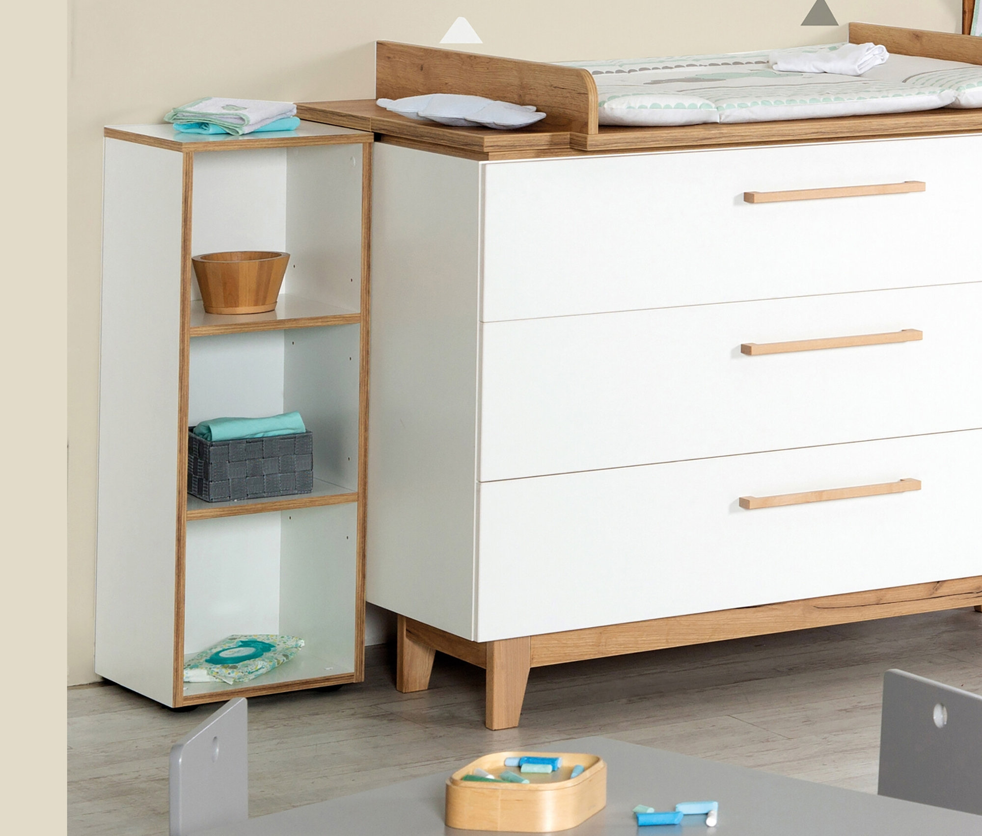 Weiße Kommode mit Wickelaufsatz und roba Seitenregal »Finn« daneben. Kindertisch und Stühle im Vordergrund.