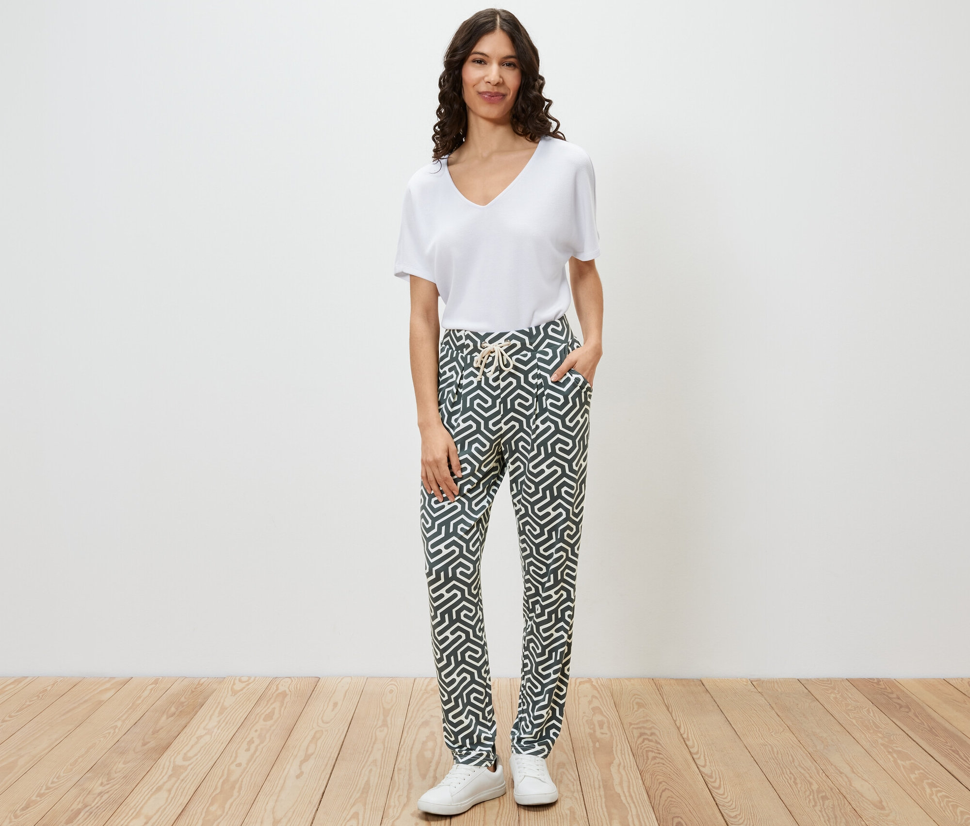 Frau posiert in einer grünen bedruckten Jerseyhose.