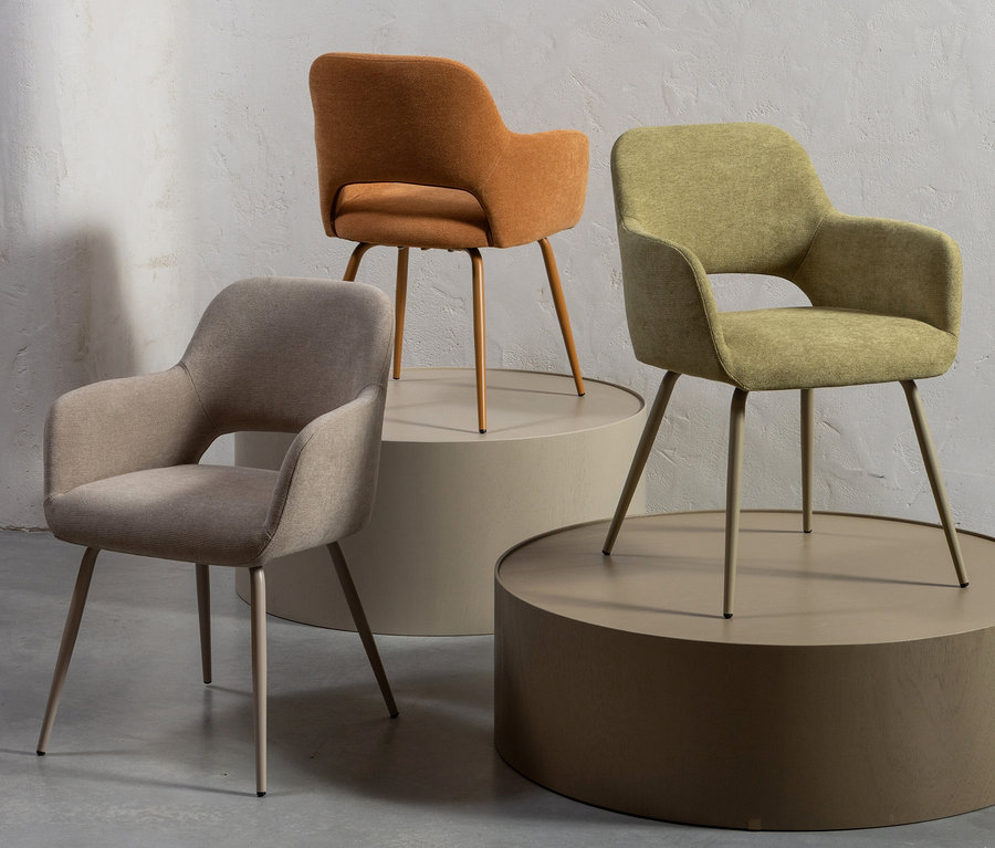 Drei Woood »Jenny« Stühle in Beige, Orange und Grün stehen auf Podesten.