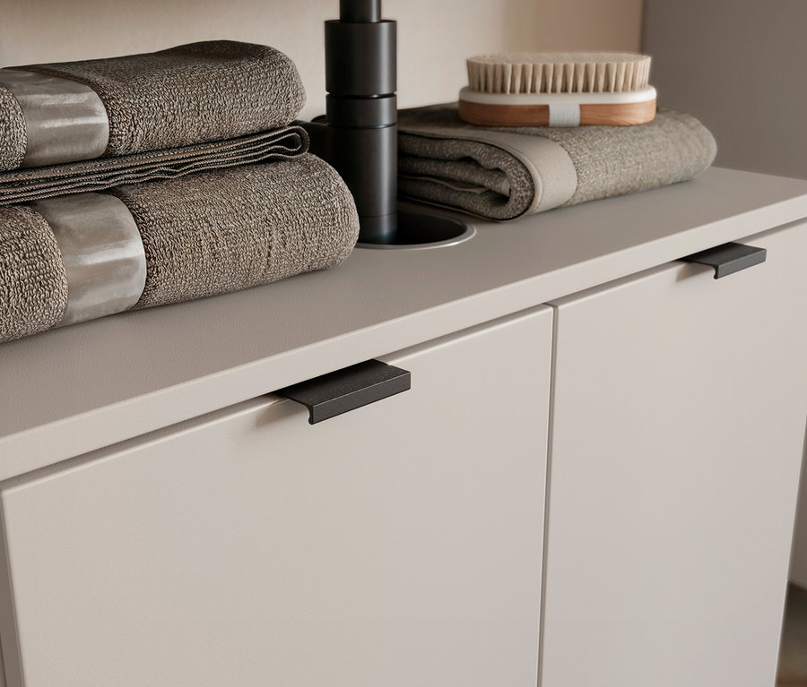 Zwei braune Handtücher gestapelt und ein braunes Handtuch mit einer Bürste darauf auf einem Waschtisch.