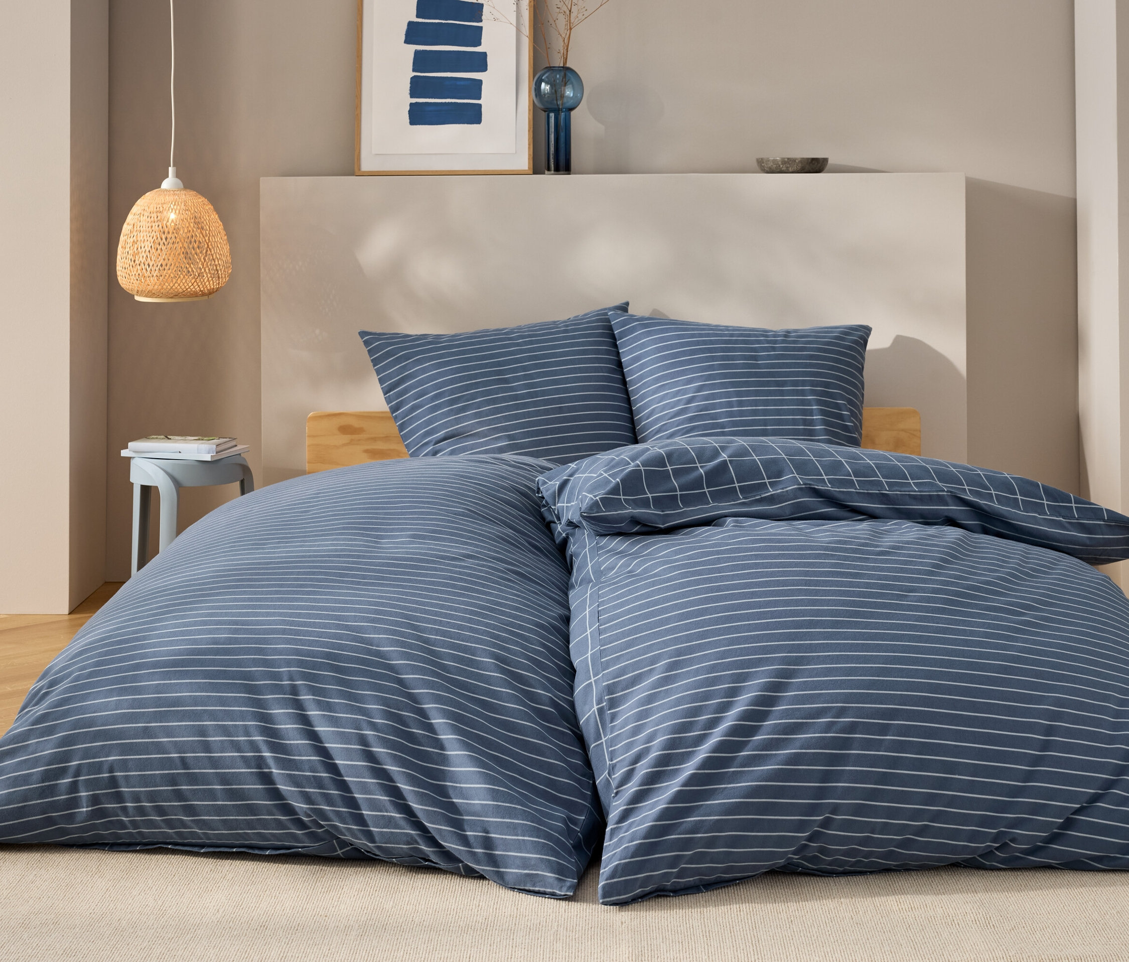 Ein blau-weiß gestreiftes Bettwäsche-Set auf einem Bett mit Holzrahmen.