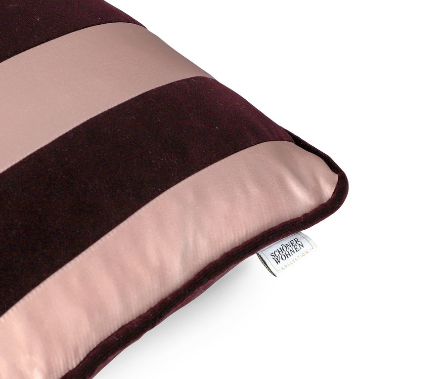 Detail einer Kissenecke mit bordeauxroten und rosa Streifen und einem Markenetikett.