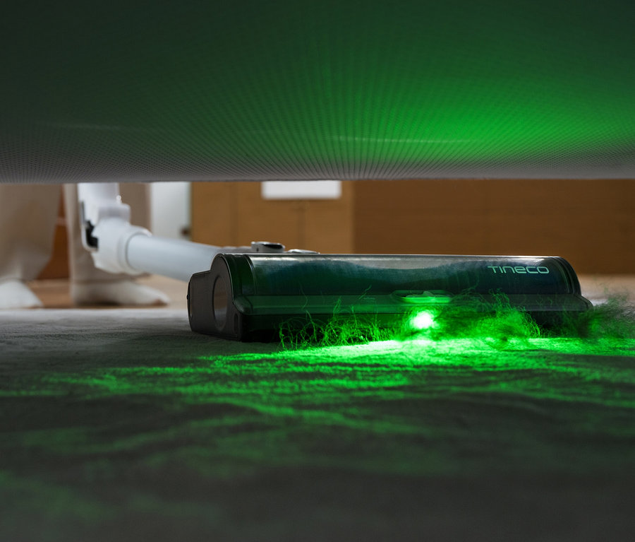 Tineco Akku-Staubsauger Pure One A50S saugt mit grünem Licht unter einem Sofa.