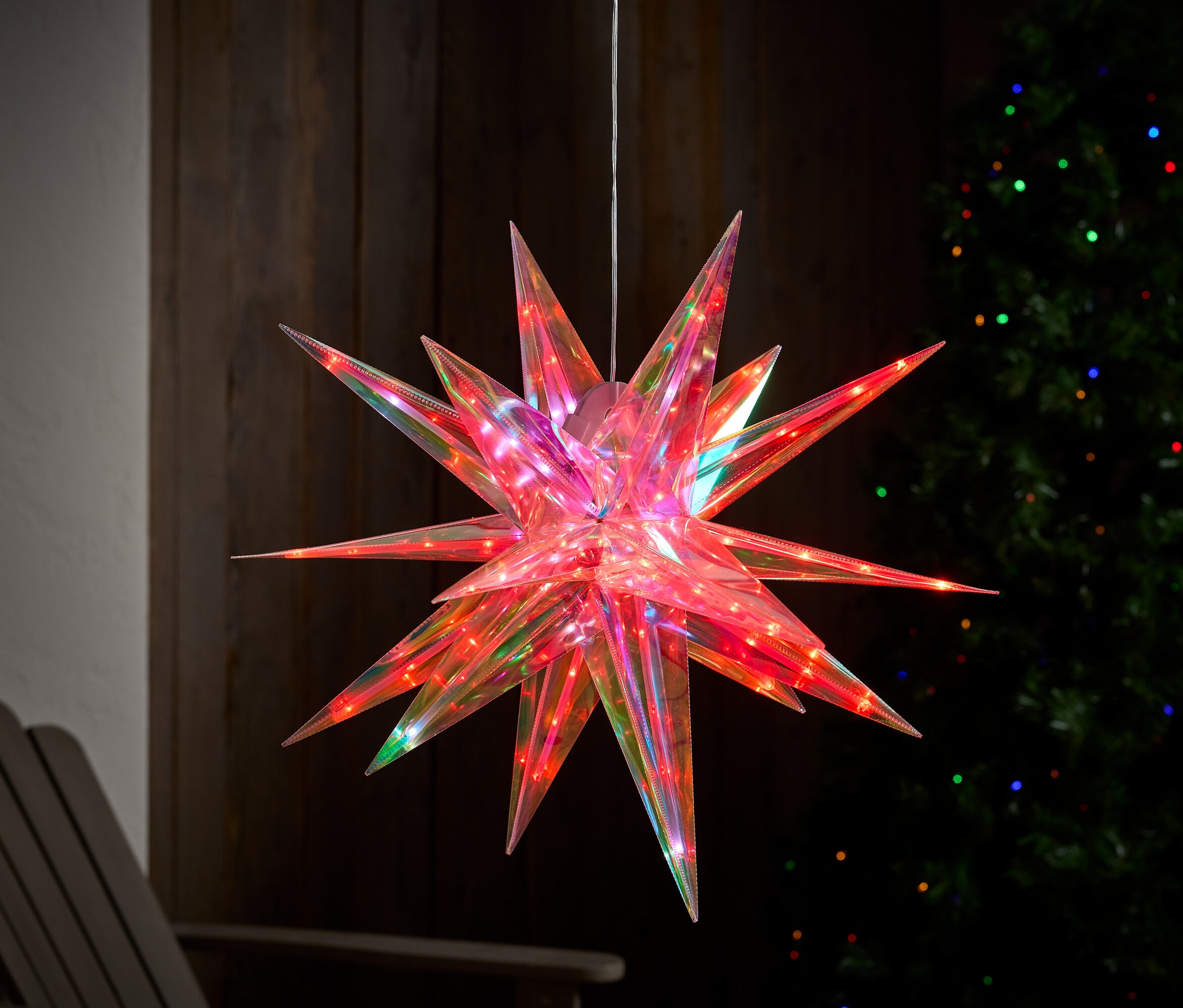 Ein hängender roter Stern mit bunten Lichtern im Hintergrund.