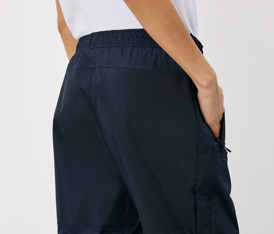 Person mit Hand in der Hosentasche einer dunkelblauen Hose mit Gummibund.