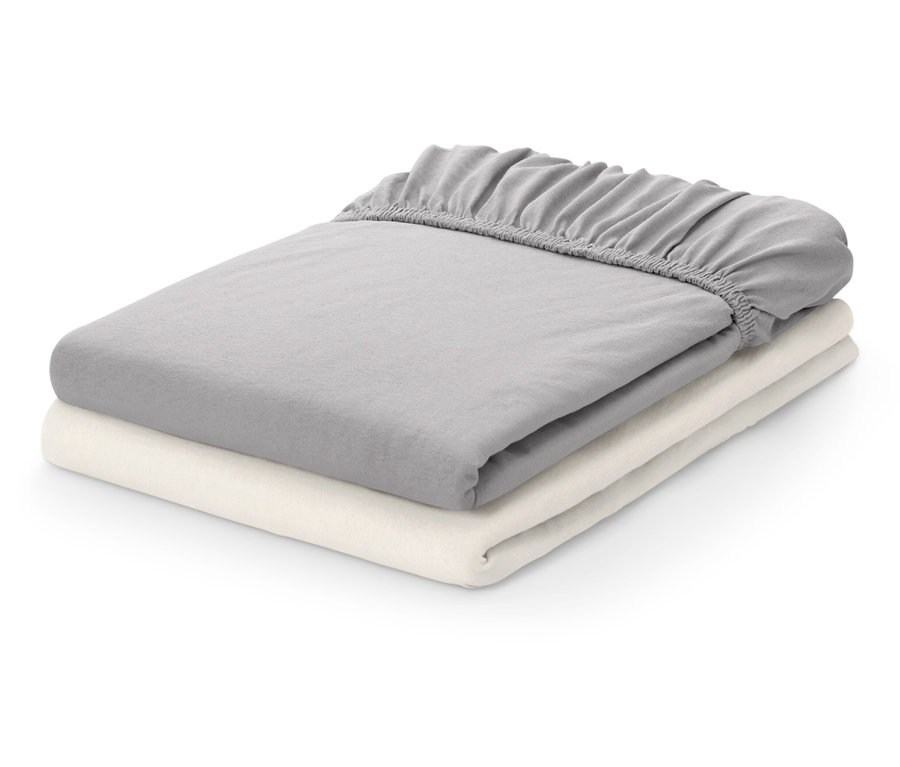 Zwei gefaltete Spannbettlaken: ein graues und ein cremefarbenes.