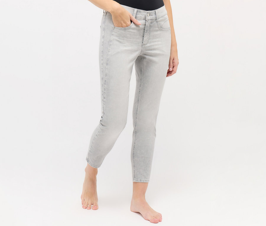 Eine Person trägt hellgraue Angels Jeans »Ornella Seam« Slim Fit 7/8, eine Hand steckt in der Hosentasche, barfuß stehend.