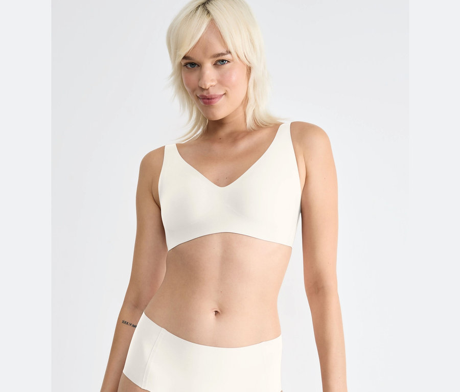 Blonde Frau trägt einen sloggi ZERO Feel 2.0 Soft Bra, silk white.