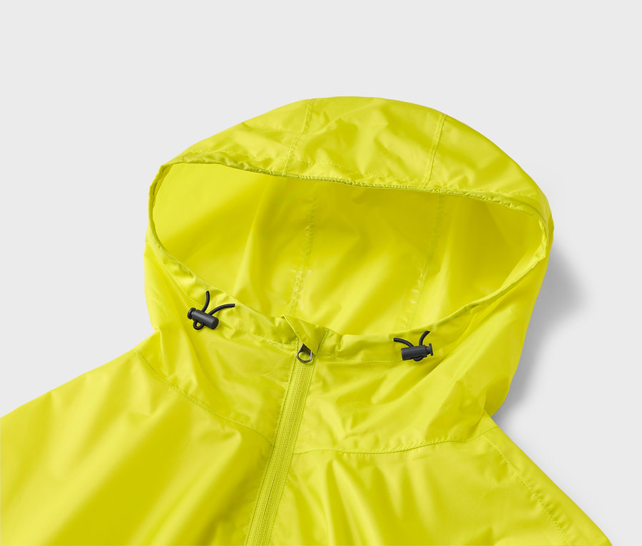 Nahaufnahme einer neongelben Regenjacke mit Kapuze und Reißverschluss auf hellgrauem Hintergrund.