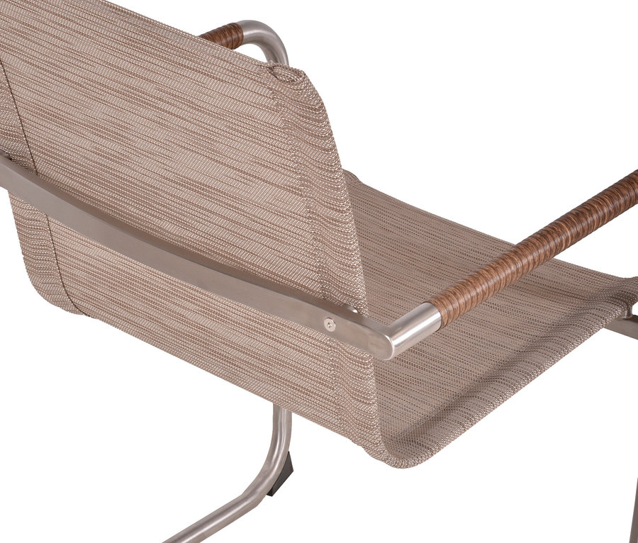 Nahaufnahme eines Stuhls mit beigem Stoffbezug, silbernem Metallrahmen und Armlehnen mit braunem Griff.
