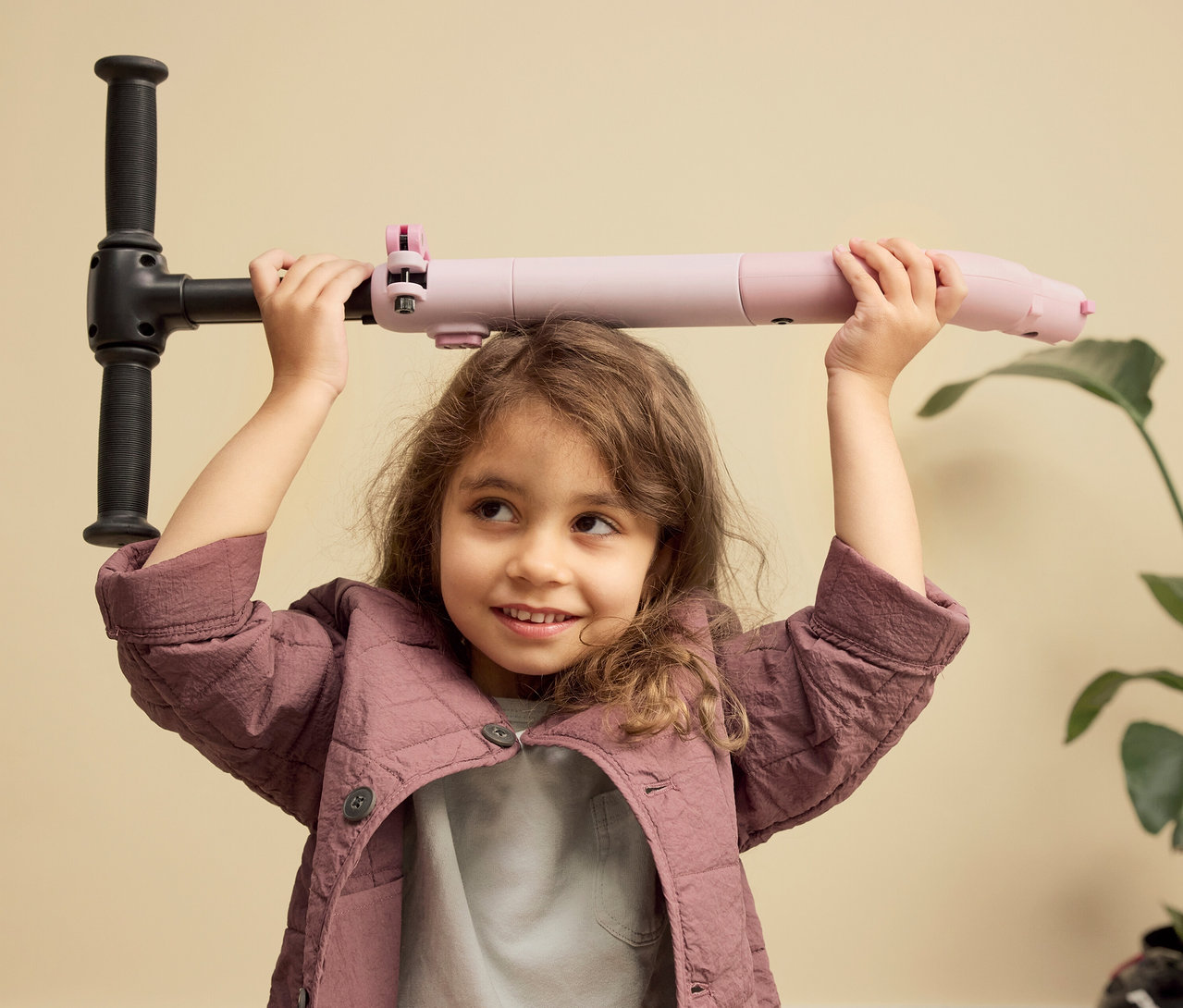 Mädchen hält PUKY Roller PUSH über dem Kopf. Der Roller ist rosa und schwarz.