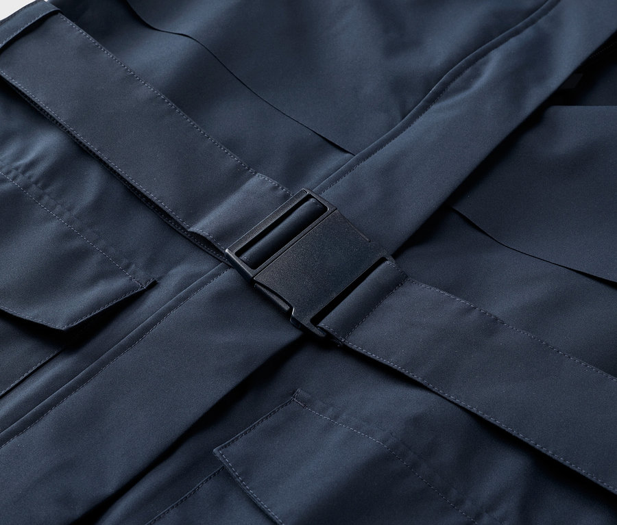 Nahaufnahme einer marineblauen Jacke mit Taschen und einem schwarzen Schnallenverschluss.