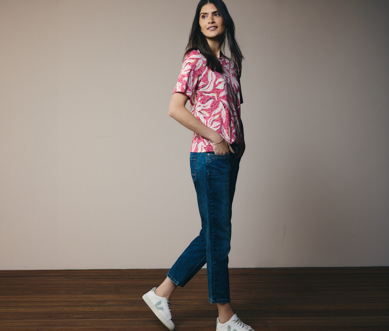 Frau geht mit rosa CECIL Kurzarmshirt und Jeans. Ihre Hände sind in den Hosentaschen.