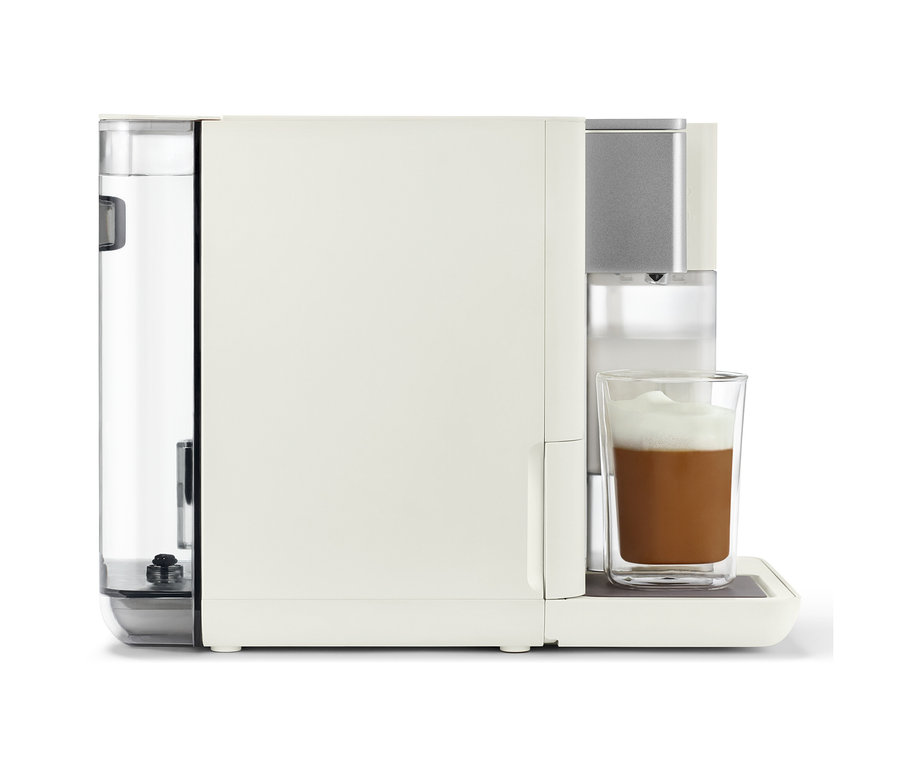 Ein Qbo MILK MASTER White Cashmere Kaffeezubereiter in Weiß mit einem Glas geschäumten Kaffee.