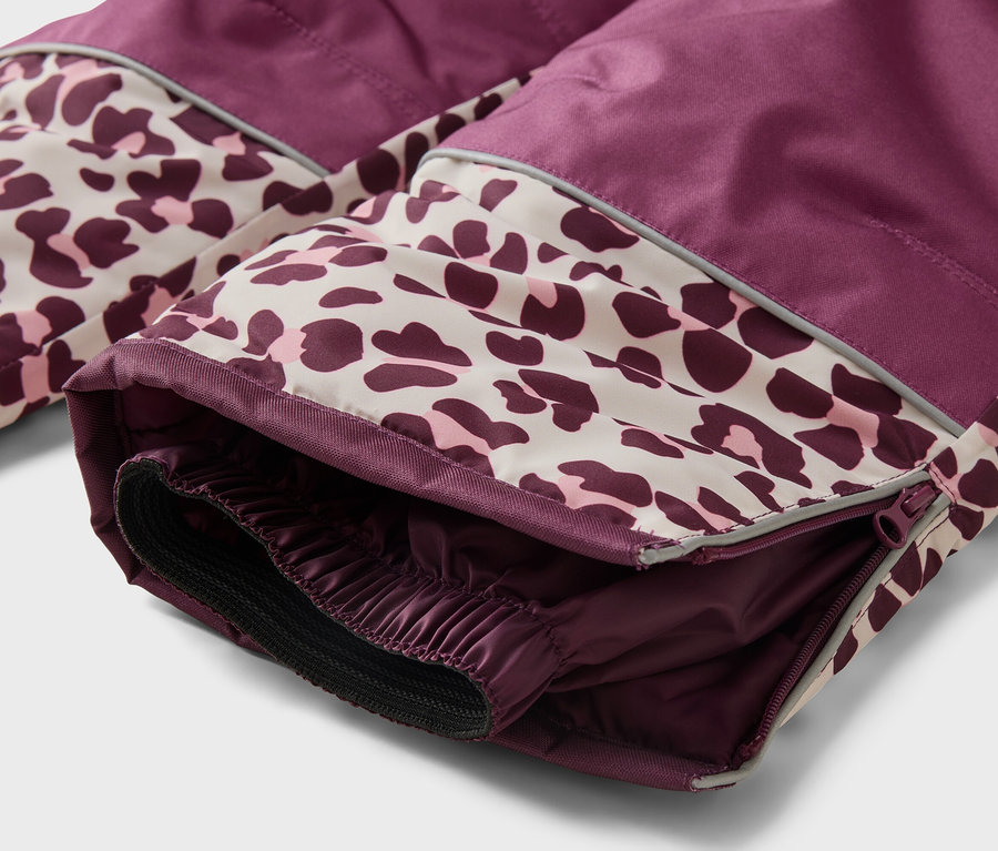 Nahaufnahme des unteren Teils einer pflaumenfarbenen und leopardenmuster-Schneehose mit Reißverschluss, Reflexstreifen und elastischem Innenbündchen.