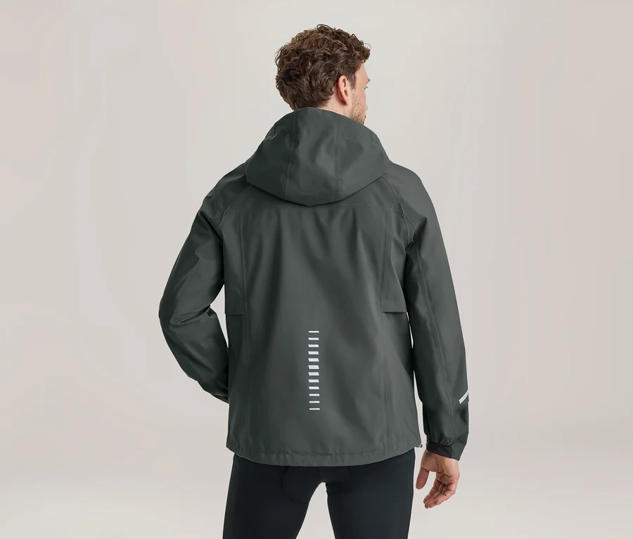 Mann von hinten in einer dunkelgrauen Kapuzenjacke mit vertikalen reflektierenden Streifen am Rücken und einem reflektierenden Streifen am linken Ärmel.
