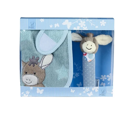 Ein Baby-Geschenkset in einer hellblau-weiß gestreiften Schachtel mit Sichtfenster. Darin befinden sich ein hellblaues Lätzchen mit einer braunen Eselkopf-Stickerei und eine Rassel mit lächelndem Eselkopf und blauem Griff mit weißen Sternen.