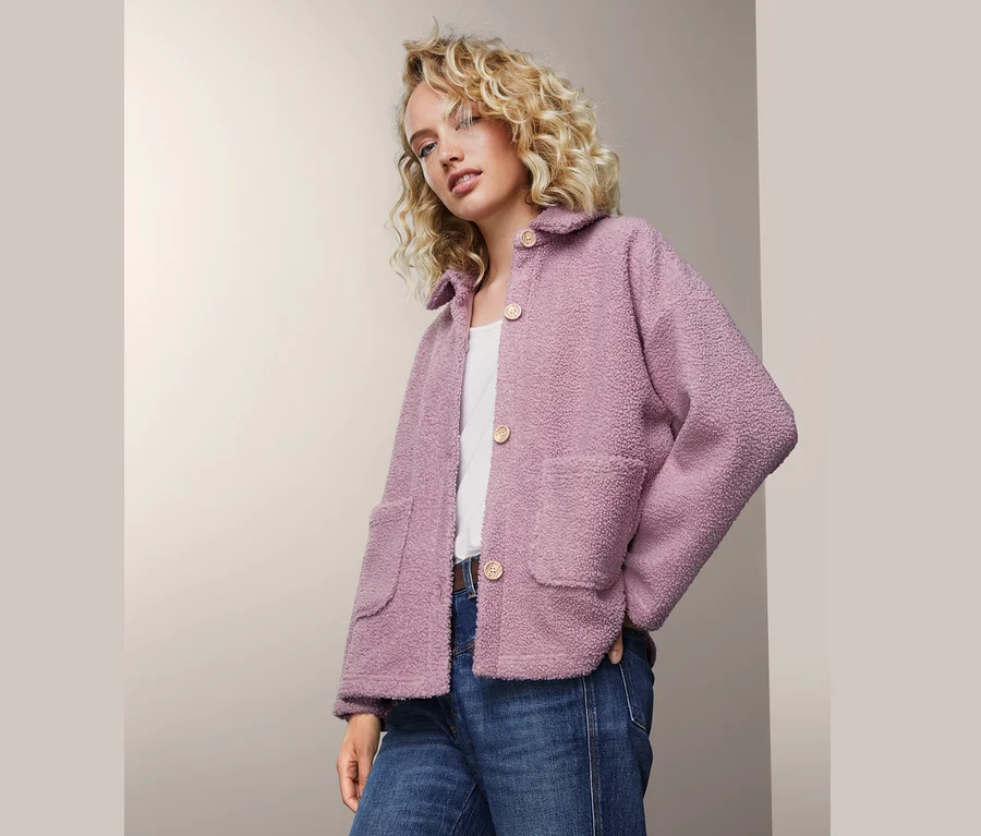 Frau trägt Teddyjacke, Jeans und weißes T-Shirt.
