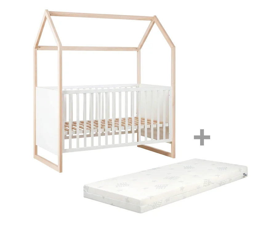 Babybett mit hausförmigem Holzrahmen und weißen Gitterseiten, daneben eine weiße Matratze mit Mustern.