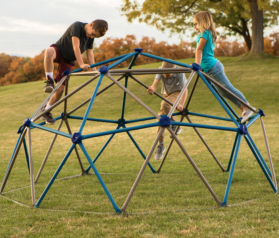 Drei Kinder klettern auf einem kleinen LIFETIME-Klettergerüst »Geodome« auf einer Wiese.