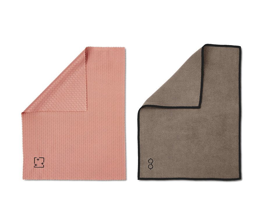 Zwei Reinigungstücher des Reinigungstuch-Sets: ein korallenrosa Tuch und ein beigefarbenes mit schwarzer Bordüre.