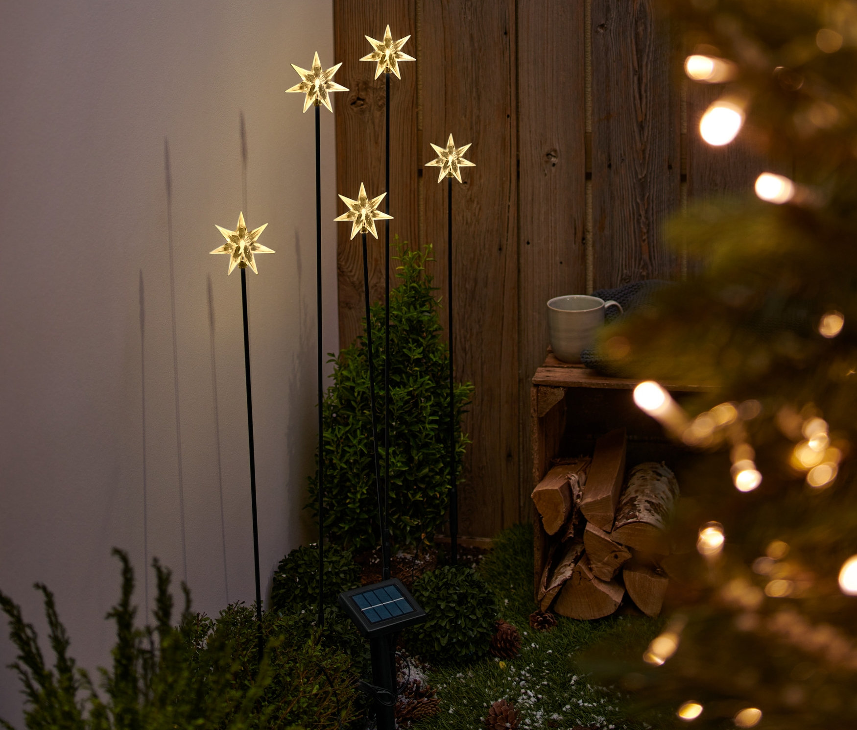 Fünf Solar-Leuchtstäbe mit Sternen in einem Garten.