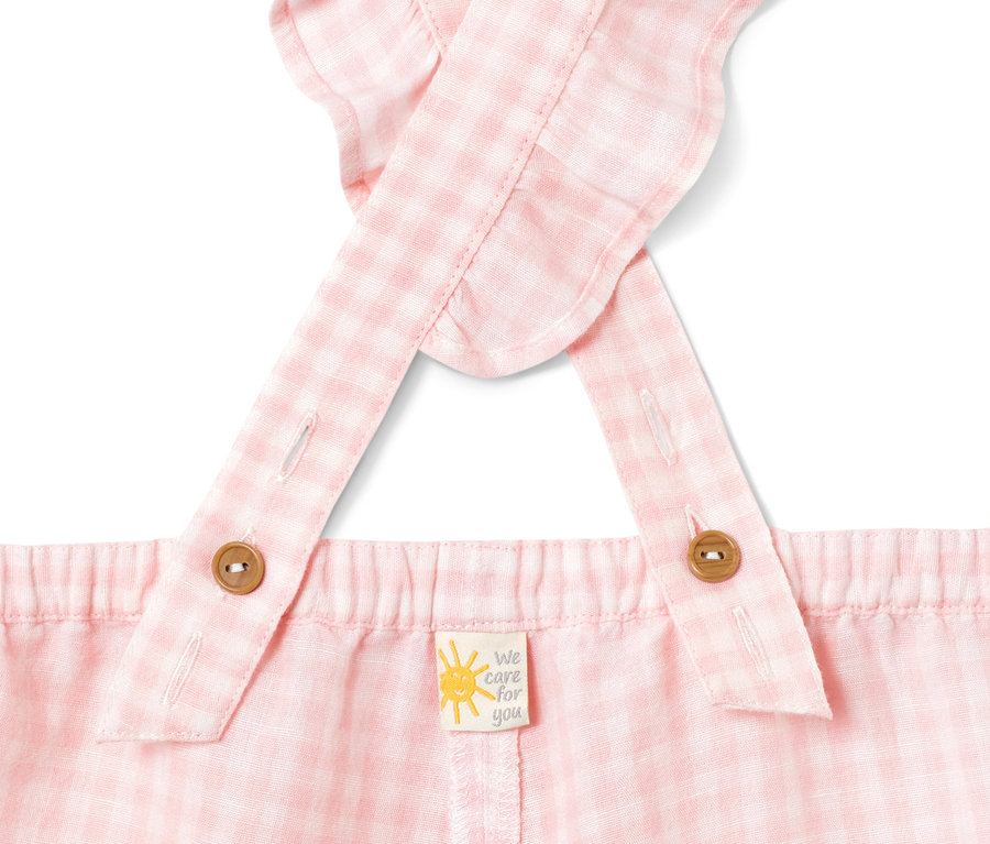 Detailansicht eines rosa karierten Jumpsuits mit Leinen und Trägerknöpfen.