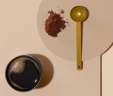 Kaffee in einer Tasse, ein Haufen gemahlener Kaffee und ein Kaffeelot.