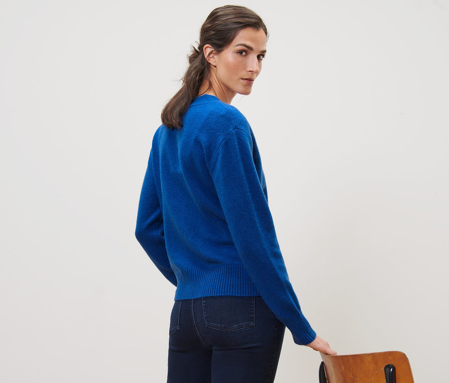 Frau blickt über die Schulter und trägt eine kobaltblaue Strickjacke mit Wolle.