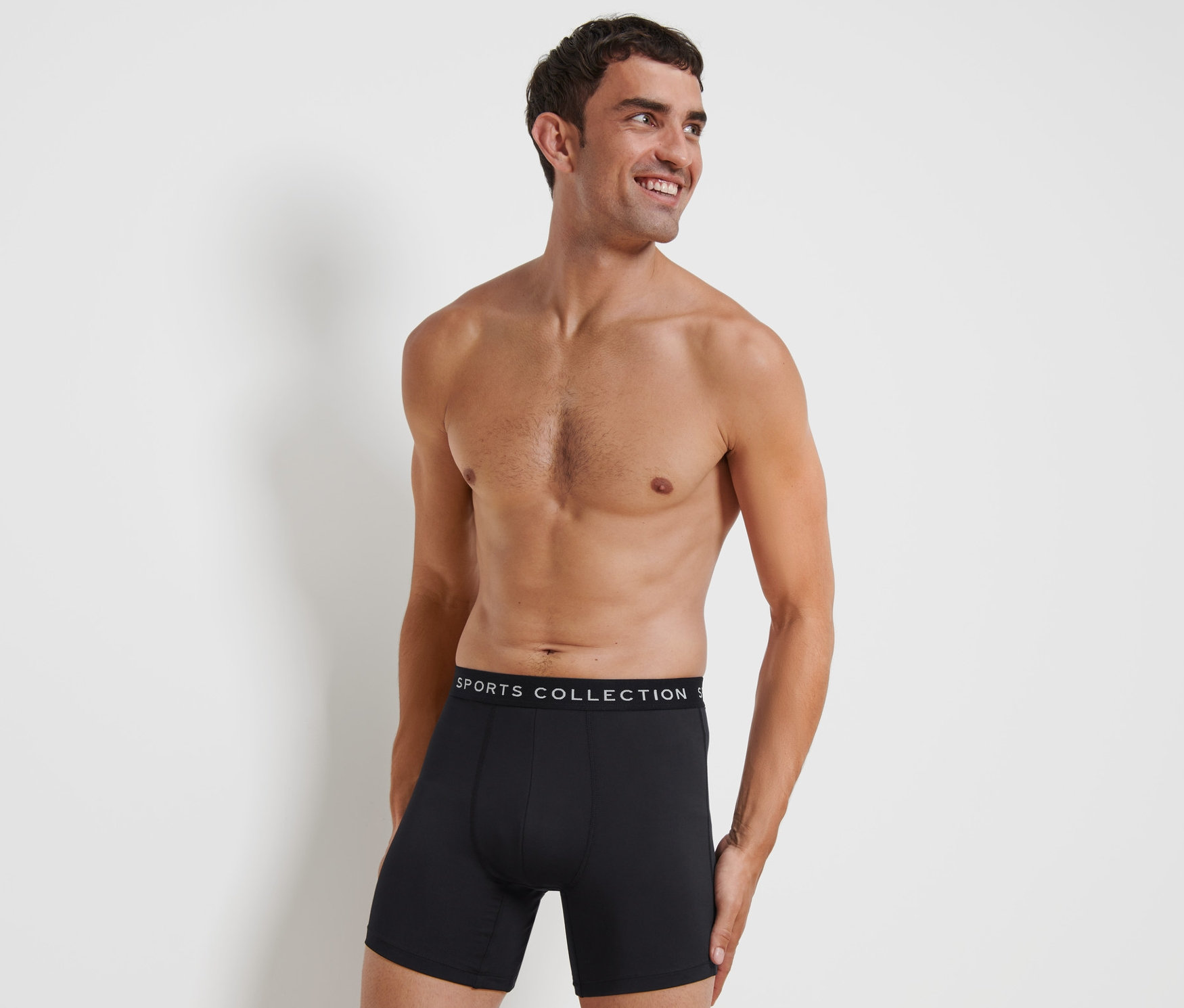 Mann lächelt und posiert in schwarzen Sport-Slipboxer.