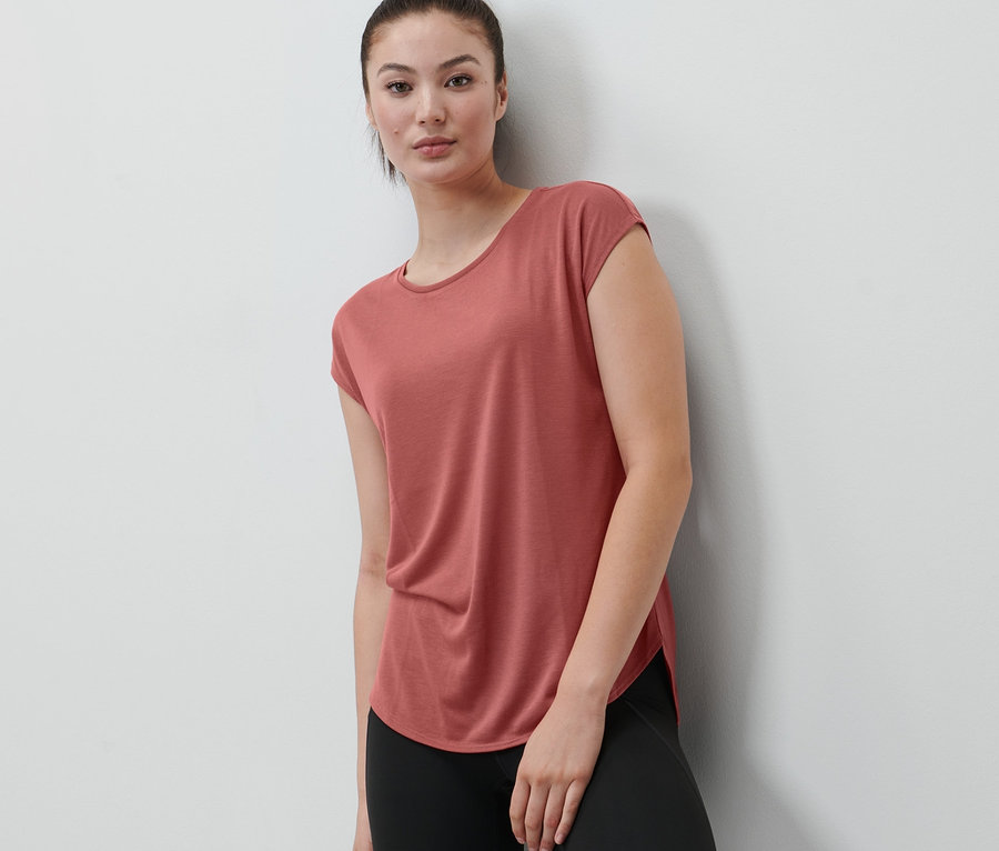 Frau trägt ein Sportshirt in Terrakotta.