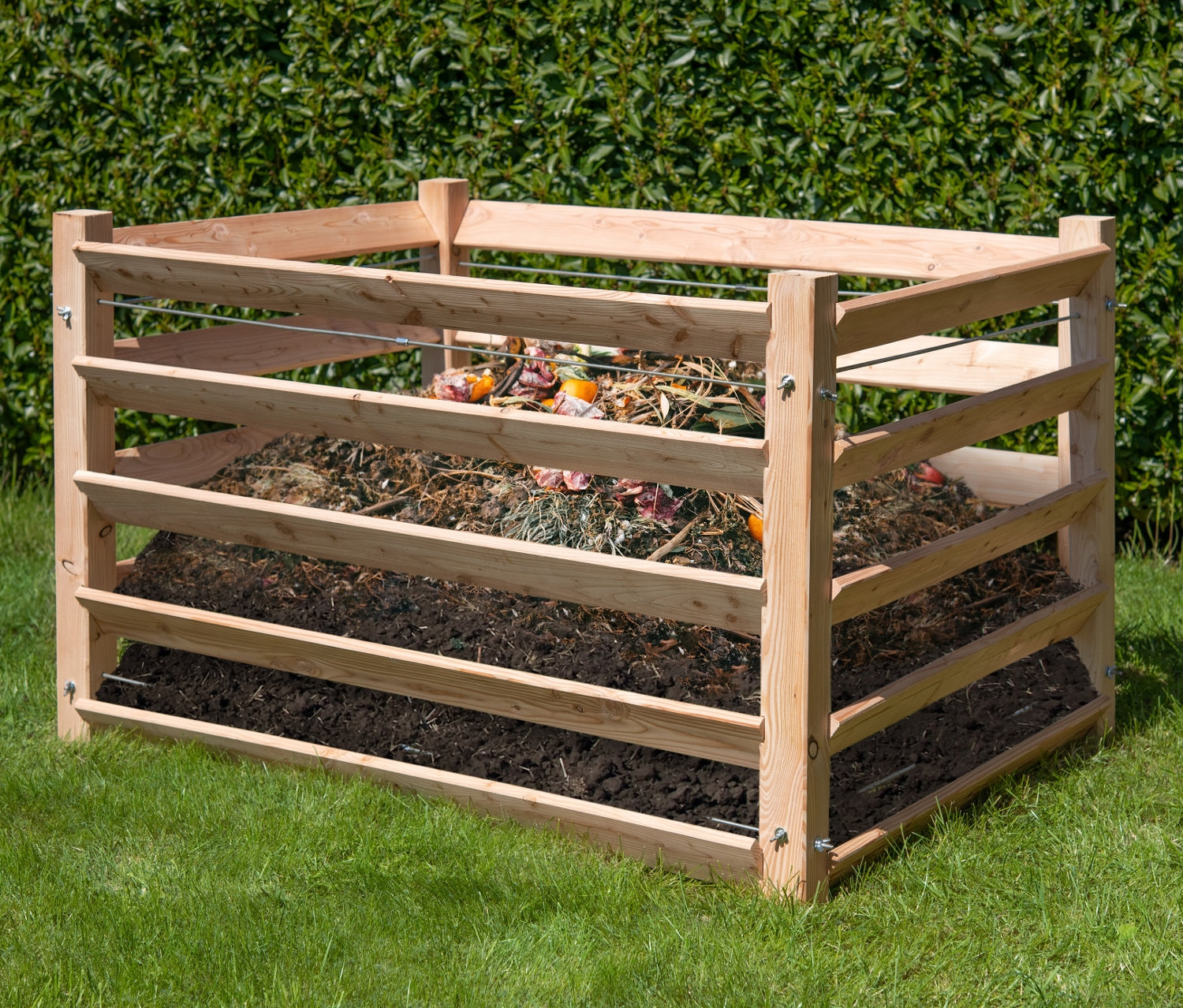 Ein 130 cm hoher Komposter Lärche aus Holz, gefüllt mit Kompost, steht auf einer Wiese.