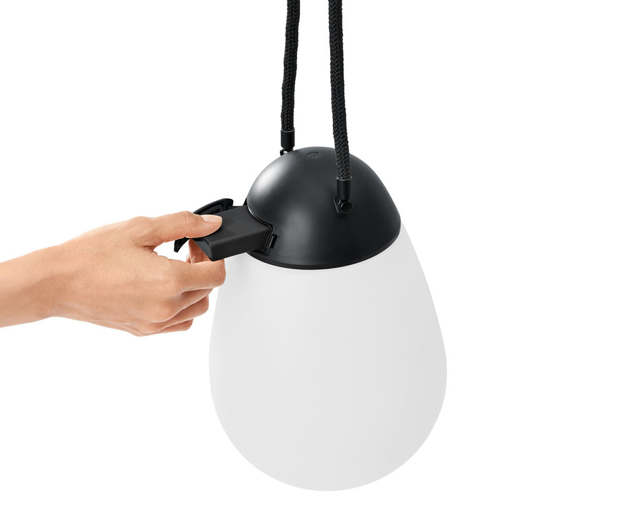 Eine Hand legt eine Batterie in eine LED-Akkuleuchte mit zusätzlichem Wechselakku ein.