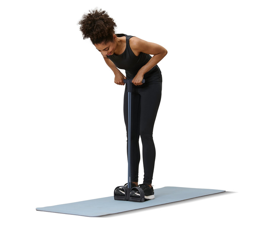 Frau trainiert mit Bauch-und-Rückentrainer auf einer Matte.