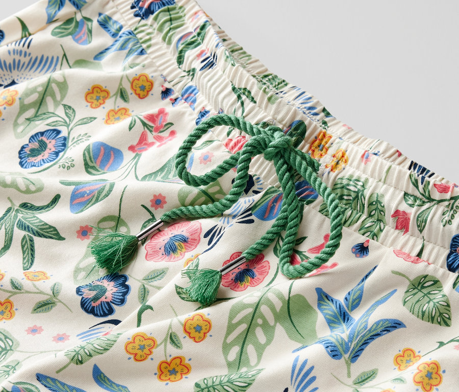 Detail einer Pyjamahose mit Blumenmuster und grünem Kordelzug in der Taille.
