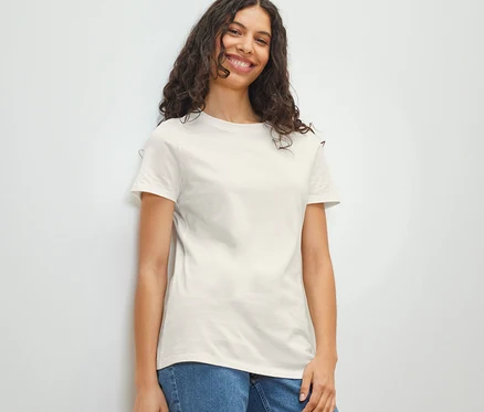 Lächelnde Frau trägt ein weißes Basic T-Shirt und Jeans.