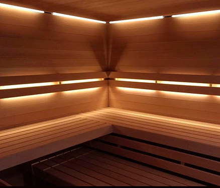 Innenansicht einer Karibu »Celie« Sauna mit Holzverkleidung und Bänken, beleuchtet mit Lampen.