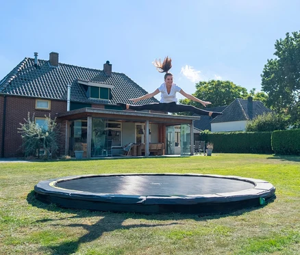 Eine junge Frau macht einen Spagat in der Luft über einem EXIT Bodentrampolin »Silhouette sports«, Ø ca. 366 cm.