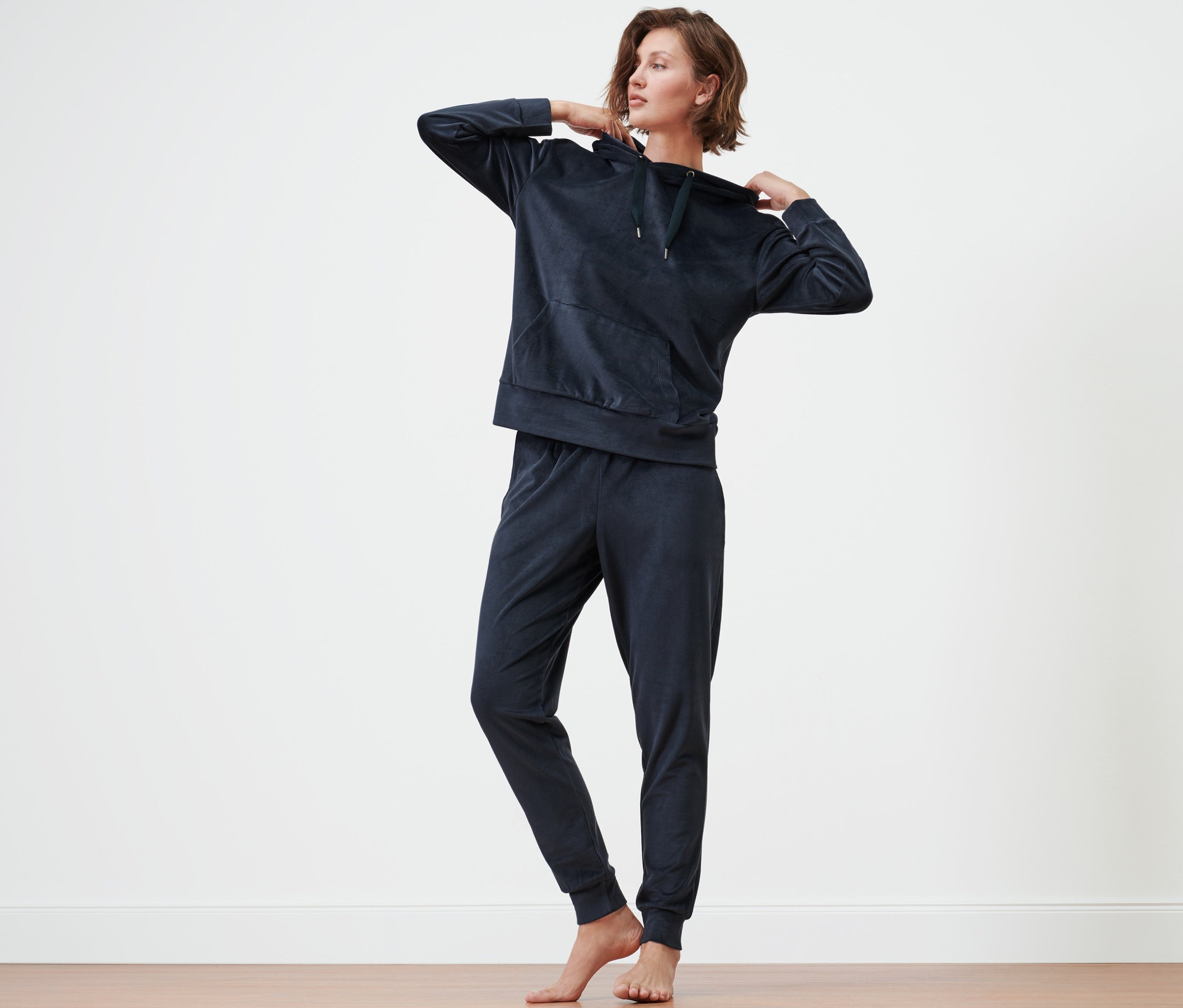 Frau richtet die Kapuze ihres Nicki-Hausanzugs.