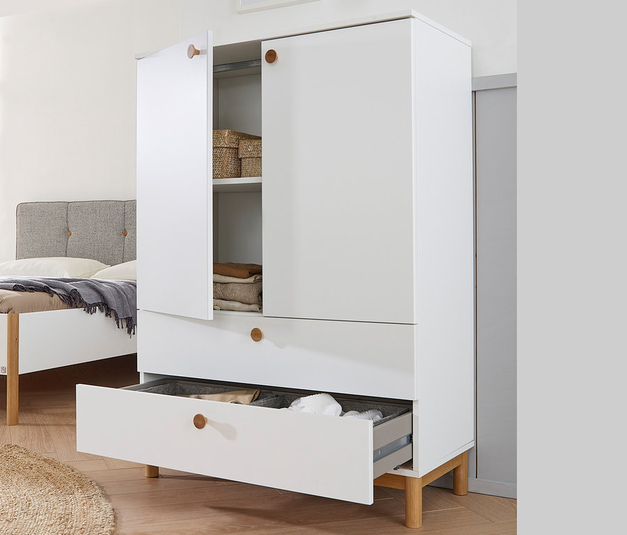 Weiße Kommode »Freyja« mit zwei Schubladen und zwei Türen, eine Tür ist offen und zeigt Regale mit Aufbewahrungskörben und gefalteter Kleidung.