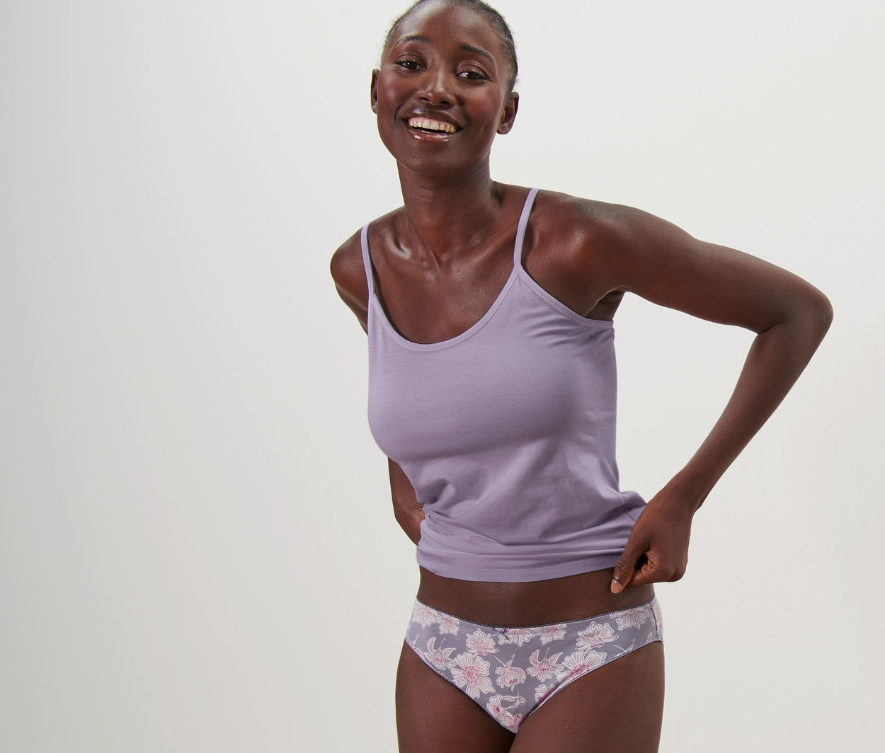 Lächelnde Frau posiert in Tanktop und 5 Slips.